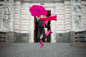 Beautiful young and happy blond woman with colorful umbrella on the street. The concept of...