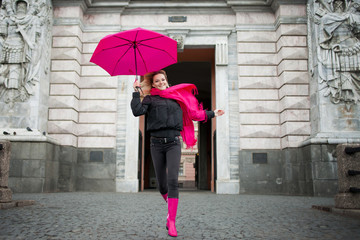 Beautiful young and happy blond woman with colorful umbrella on the street. The concept of positivity and optimism