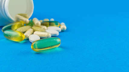 Supplement of omega-3 capsule on foreground in the focus, vitamin complex, glucosamine capsules and white container on blue background