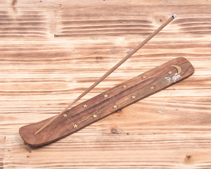 Hand carved burner, holder with sandalwood incense on wooden vintage background