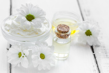 Fototapeta na wymiar camomile essential oil in glass bottle in cosmetic set on table background