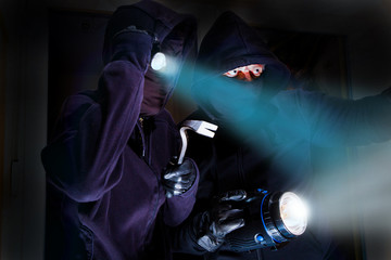 zwei Einbrecher mit Taschenlampen sind in ein Gebäude eingedrungen