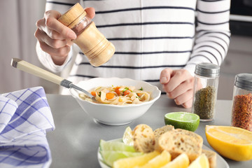 Woman eating chicken noodle soup at kitchen table