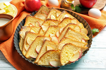 Tasty bread pudding with apple in baking dish on table
