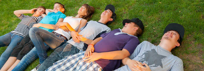 Teenage boys and girls lying on the grass on beautiful sunny spring day