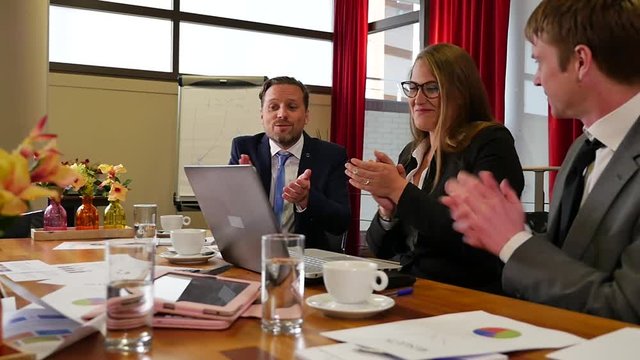Happy business team applauding at boardroom meeting in slowmotion. Dollyshot.
