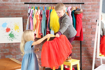 Cute little children choosing clothes in dressing room