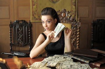 Beautiful girl with creative make-up and a lot of dollars in retro office. © Evdoha