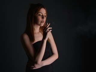 Fototapeta premium young woman with cigarette, smoking concept on black background