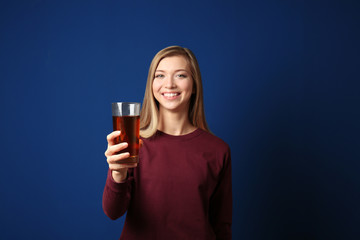 Beautiful young woman with glass of fresh juice on dark blue background