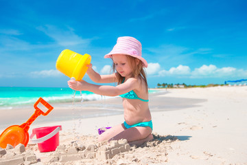 Adorable little girl playing with beach toys on white sandy beach