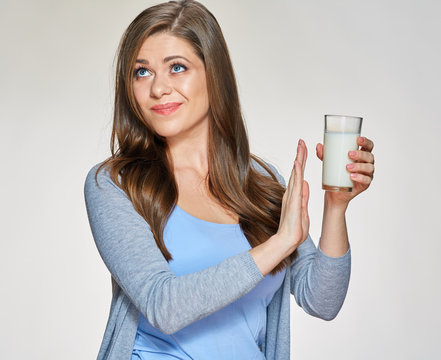 Young woman holding milk glass with disgust emotion.