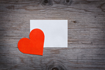 Red paper heart Valentine's card with a clean white sheet of paper. Space for text. Wooden background texture