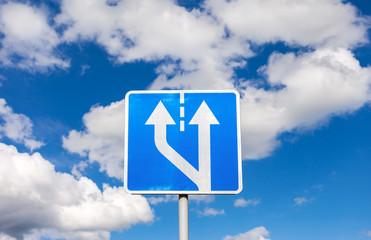 Road sign against the blue sky with clouds