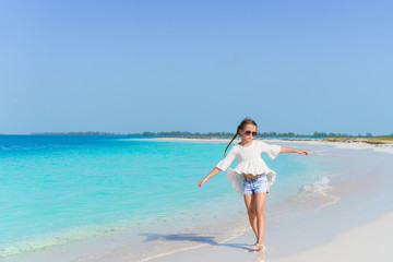 Fototapeta na wymiar Adorable little girl walking along white sand Caribbean beach