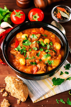 Goulash in ceramic bowl on wooden background. Traditional hungarian soup.