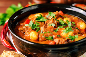 Goulash in ceramic bowl on wooden background. Traditional hungarian soup.