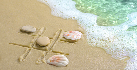 Fototapeta na wymiar A tic tac toe game drawn in the sand on the beach.