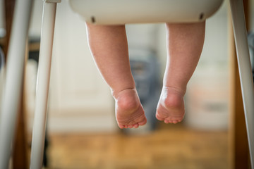 Little child sitting on the high chair  , Close up of babies legs while he is sitting in high chair