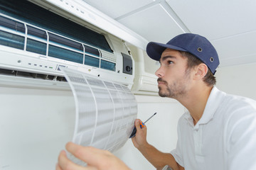 portrait of mid-adult male technician repairing air conditioner