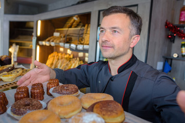 Confectioner showing tray of cakes