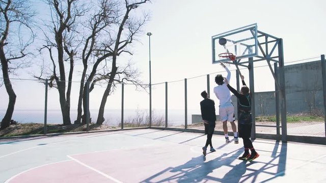 Group of people playing basketball outdoors, slow motion