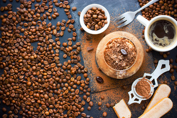 Traditional Italian dessert tiramisu cake in glass on table with ingredients