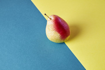 Whole fresh ripe pear, fruit view from above on blue yellow background, modern style food picture, wallpaper design