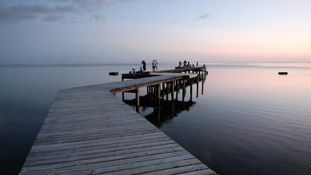 Wooden jetty and silhouette of people at sunset, Tahiti, South Pacific