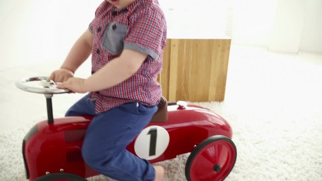 Small boy driving a toy car in the room