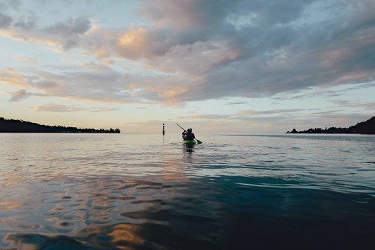 People kayaking on the water at sunset