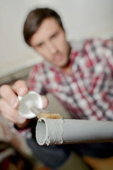 Man putting plastic glue on end of pvc pipe