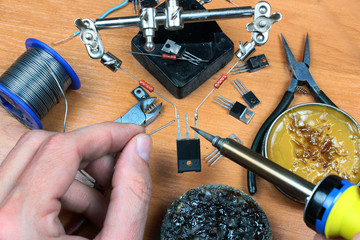 Fototapeta na wymiar Hands holding soldering iron and solder wire. Electronic parts being connected together.