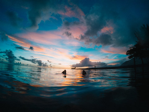 Feet poking out of sea at sunset, Tahiti, South Pacific 