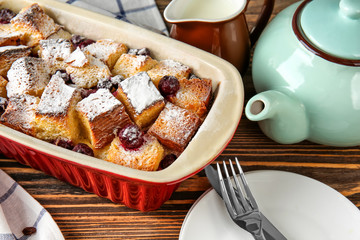 Freshly baked bread pudding in casserole dish on wooden table