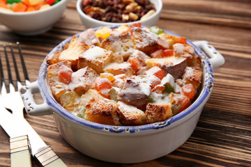 Freshly baked bread pudding in casserole dish on wooden table