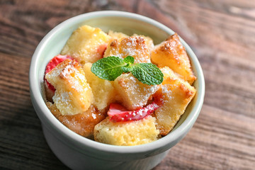 Delicious bread pudding with strawberry and mint on wooden table