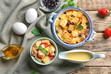 Delicious bread pudding with berries and mint on wooden table