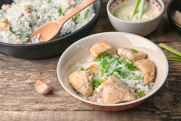 Plate with tasty chicken and rice on wooden table