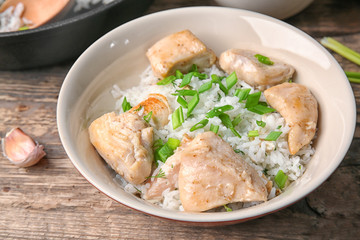 Plate with tasty chicken and rice on wooden table