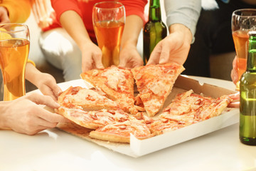 Hands of friends taking slices of tasty pizza from cardboard box at home party