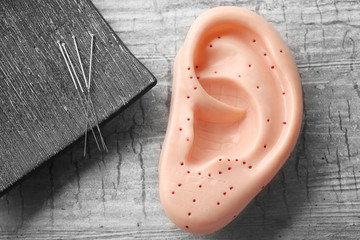 Set of needles for acupuncture and plastic mockup of human ear on grey background