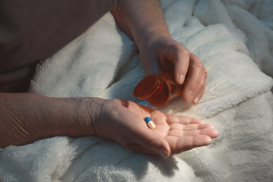 Elderly woman with pills at home, closeup