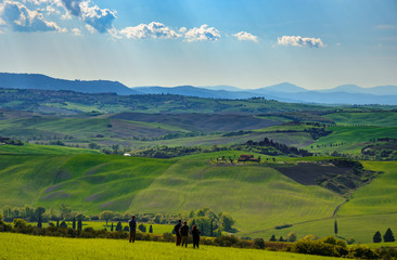 View of Tuscany countryside in spring with a group of tourists who admire the panorama.