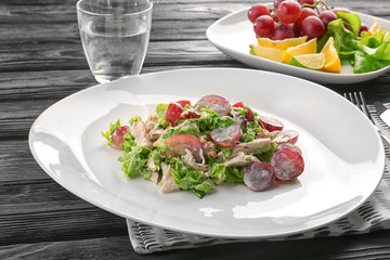 Plate with chicken salad and grapes on table