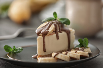 Tasty cheesecake slice with chocolate and bananas on plate