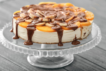 Tasty cheesecake with fruits and chocolate on stand