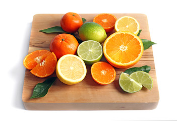Wooden board with delicious citrus fruits on white background
