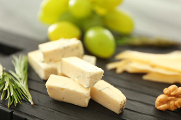Composition of sliced cheese and walnut on black wooden board