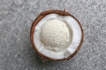 Fresh ball of ice cream in half of coconut on grey background